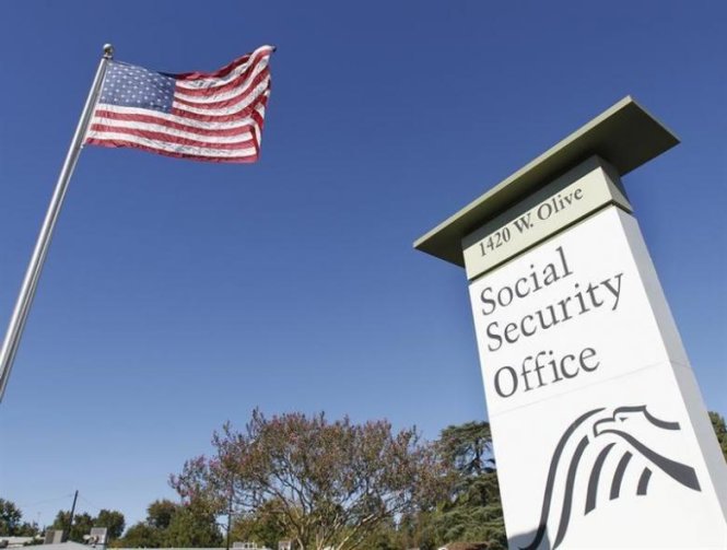 An American flag flutters in the wind next to signage for a United States Social Security Administration office in Burbank, California October 25, 2012. REUTERS/Fred Prouser