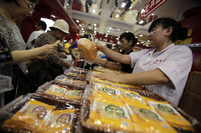 In this Sept. 12, 2013 photo, a vender, right, sells mooncakes to a customer, left, at a shop in Shanghai, China. The mooncake, a traditional pastry thats given during the Chinese mid-autumn festival, has become the unlikely latest casualty of Beijings anti-corruption campaign. (AP Photo/Eugene Hoshiko)